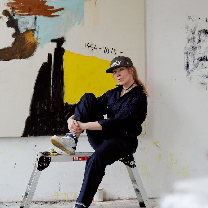 Jenny Brosinski sat with a knee raised towards her face on a step-ladder in her studio