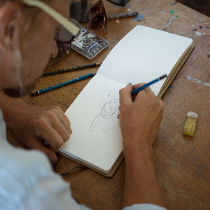Seth Globepainter drawing in a small sketchpad in his studio