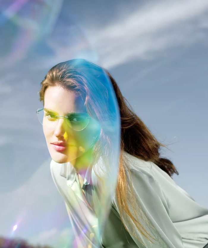 Femme regardant à travers une bulle de savon colorée portant The Wave avec des branches de couleur menthe