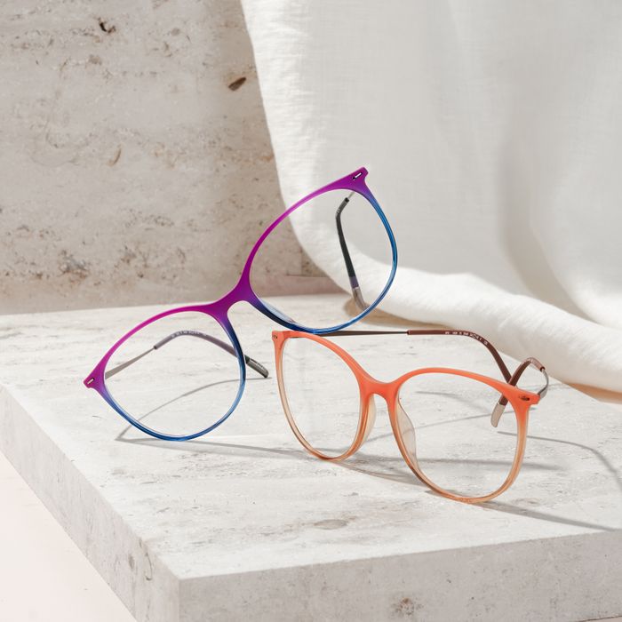orange and purple-blue full-rim glasses on a beige stone plate