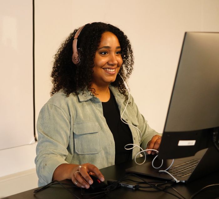 Woman with headphones looking at a computer screen