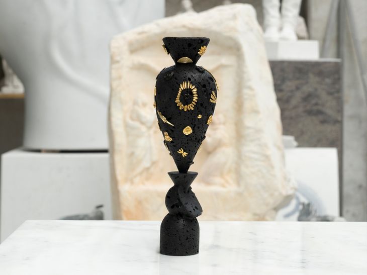 black basalt rock sculpture with bronze details on a white marble table