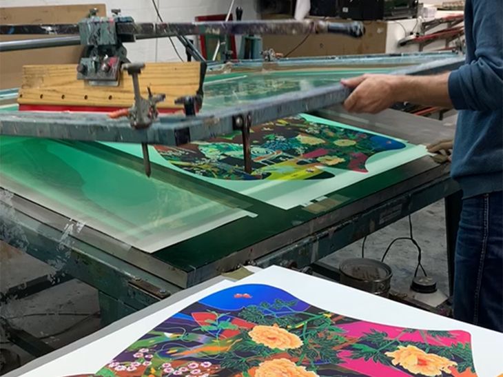 print workshop applying varnish highlights to the surface of a colourful screenprint