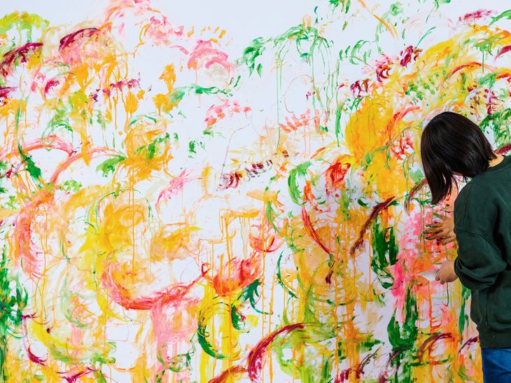 artist Ayako Rokkaku hand-painting a large white canvas
