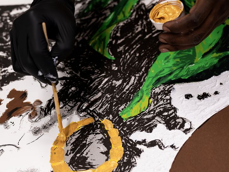 Khari Turner adding gold paint to a circle of an earring