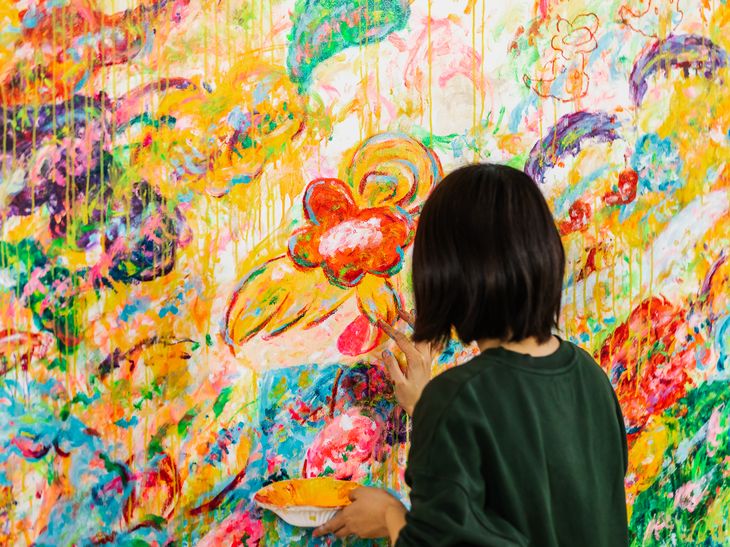 Ayako Rokkaku adding eyes to the figure at the centre of a large painting