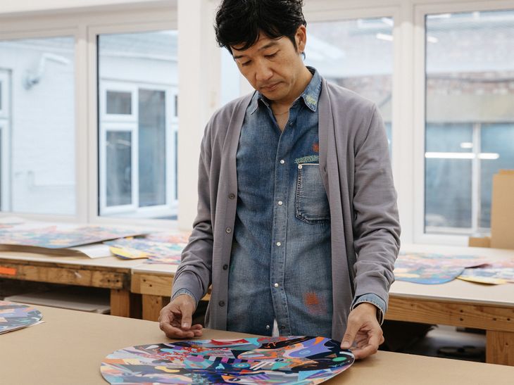 artist behind table inspecting finished screenprint in the shape of two intersecting circles