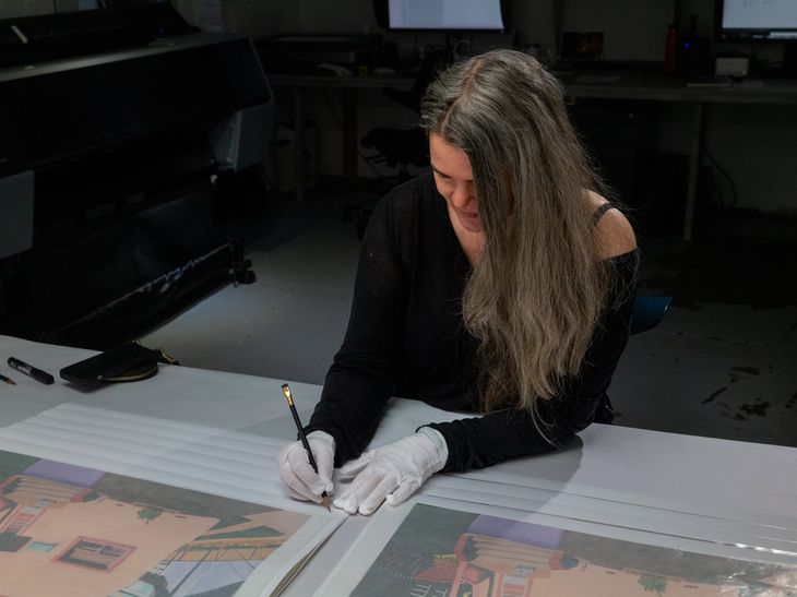 Gabrielle Garland wearing white gloves and signing a print in thick back pen