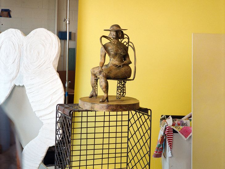 bronze sculpture in front of bright yellow paper backdrop in studio space