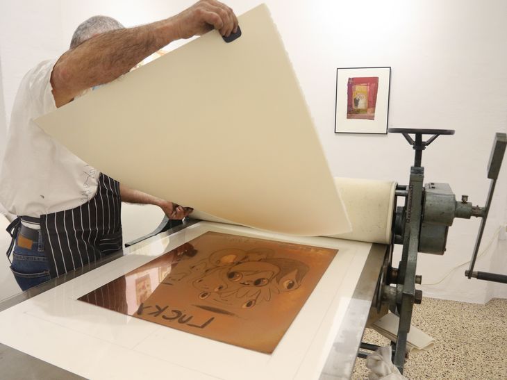 print maker lifting a finished print by Javier Calleja in the lithography workshop 