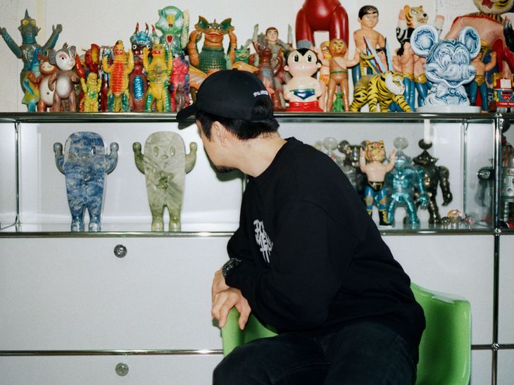 Haroshi sat in his studio looking back to two GUZO sculptures