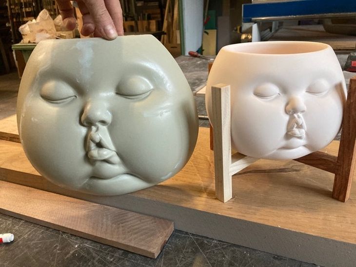 preparatory case for baby-faced plant pot held alongside finished porcelain sculpture