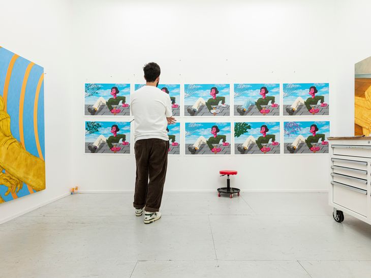 Nicasio Fernandez hand-finishing a print edition taped up to a white wall