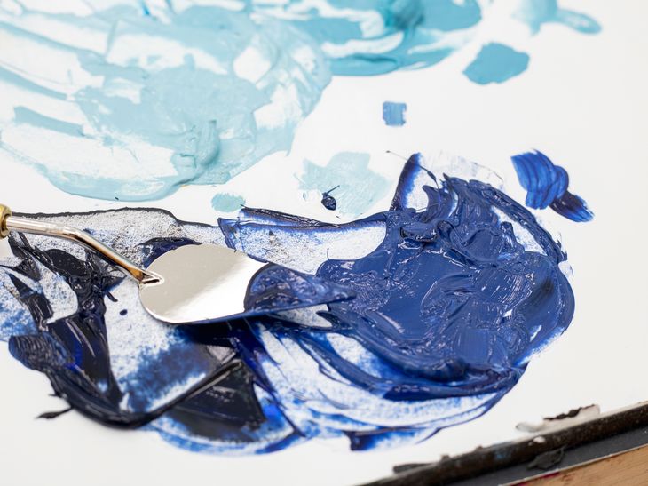 a palette knife dipped into blue oil paint