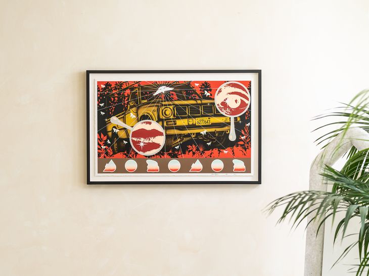 a framed print edition by Jaime Munoz photographed hung on a white wall above a chair 
