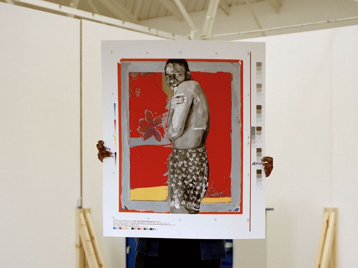 artist holding up a large portrait with a red background