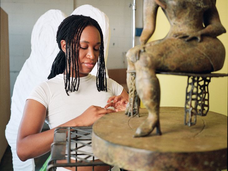 Tschabalala Self sitting behind the final proof for her patinated bronze sculpture edition