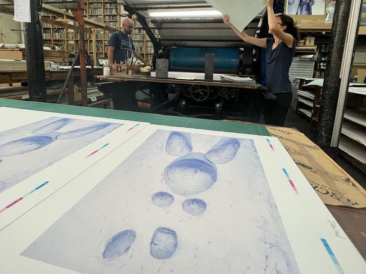 a series of lithograph prints being taken off a nineteenth century press