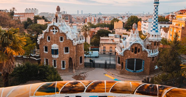 tan stone buildings covered with white mosaics along the roof at park guell in barcelona spain