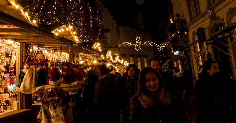 people walking around the european christmas markets at night