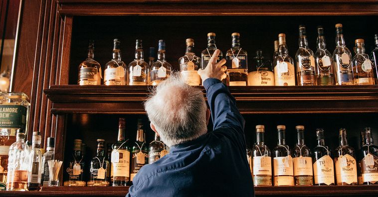 man reaching for liquor in an irish bar