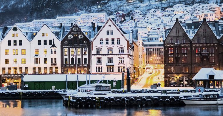 snow capped buildings in bergen norway during the evening