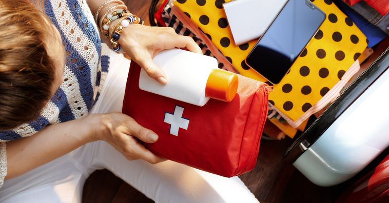 overhead view of woman packing first aid kit for traveling