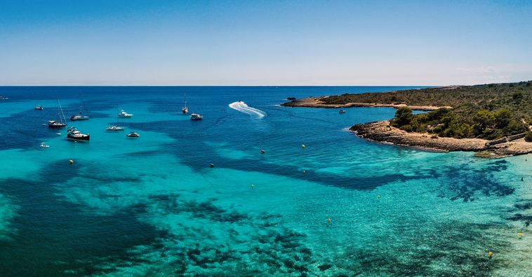 boats docked in the crystal blue water off the coast of Menorca in Spain
