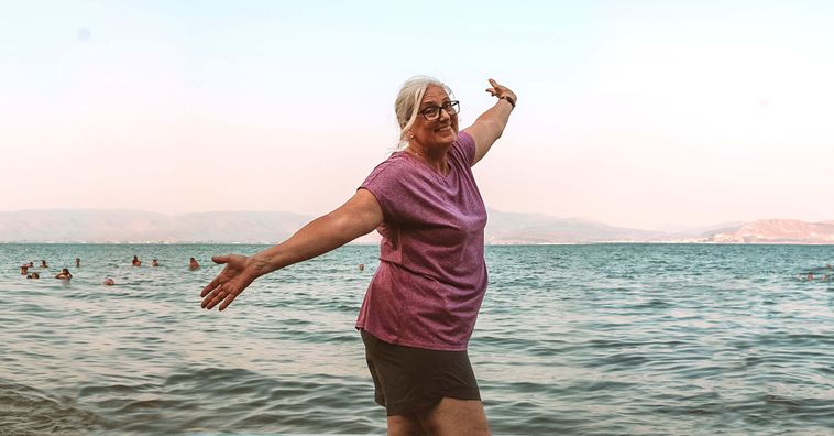 woman hands in the air at the beach in nafplio in greece