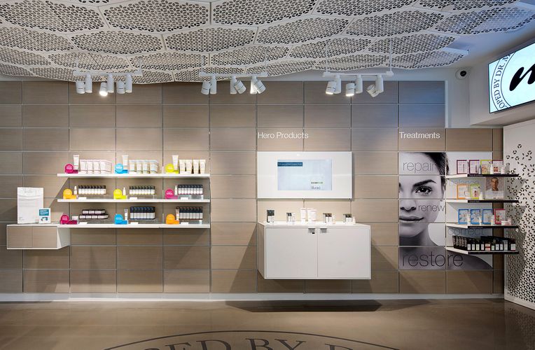 A wall from the Murad shop. White System 1224 shelves are lined against it showcasing various skincare products.
