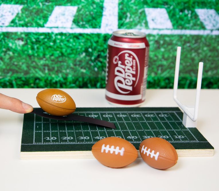 Spielzeug-Football-Feld mit Footballs und Dr Pepper Dose