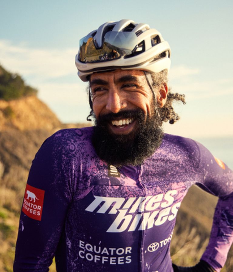 A man with beard is smiling in cycling suit