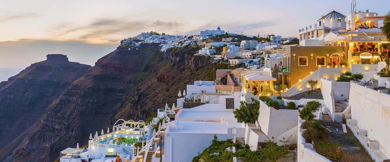 Fira Town in Santorini, lit up at night at dusk.