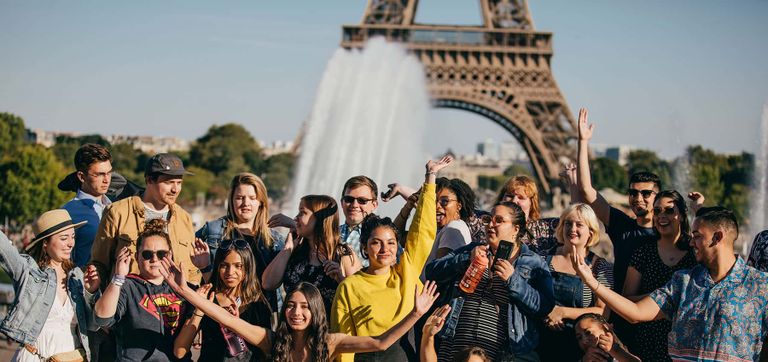 A group of travelers posing for a photo in front of the Eiffel Tower in Paris