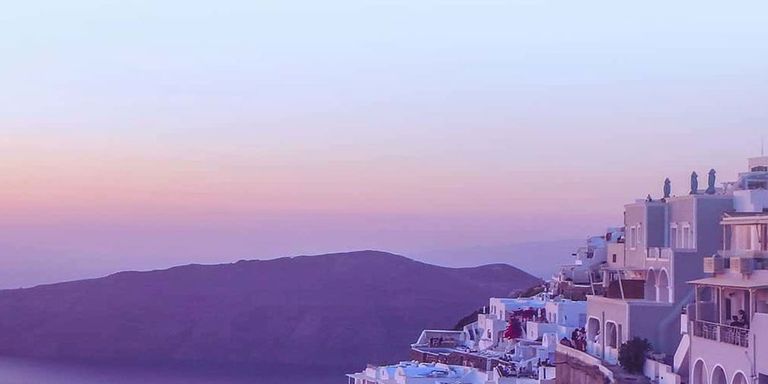 Scenic shot of Greece cliffside at sunset with a purple sky