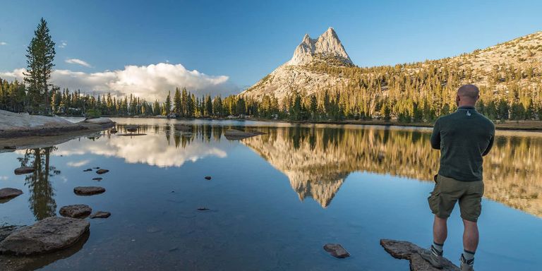 Man overlooking the calm, glass-like waters of Cathedral Lake in Yosemite National Park.