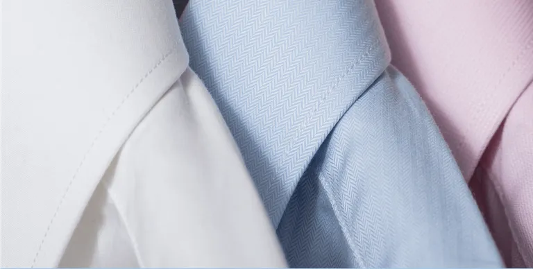The collars of a white, blue, and pink button-up shirts.