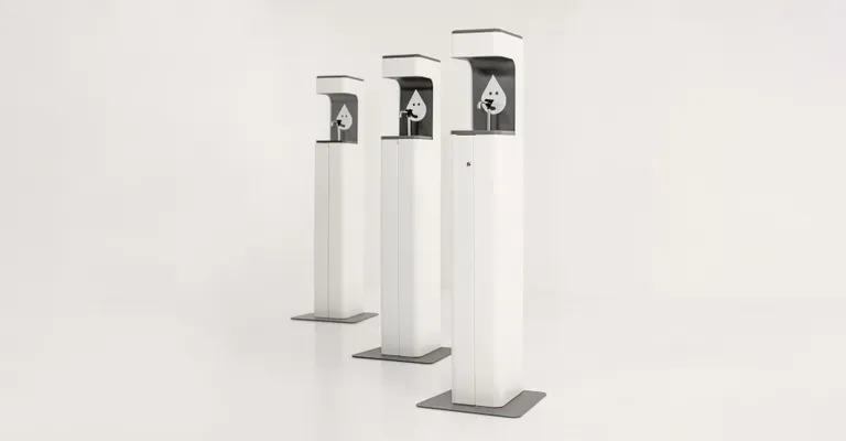 Three white tall sanitizing stations are lined up diagonally, the one on the right being the closest and left farthest.