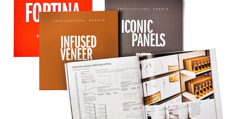 Various magazines are spread across the image labelled "Fortina", "Infused Veneer", and "Iconic Panels" respectively. The magazine sitting above the rest is open to a spread with architectural drawings and an image of shelves displaying boxes and bottles.
