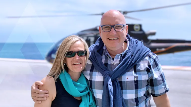 Brian Llyod standing with his partner in front of a helicopter