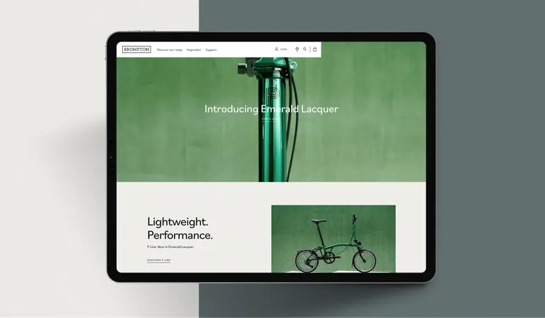 A tablet screen displays the Brompton Bicycle home page. It has a green and white coloured theme
