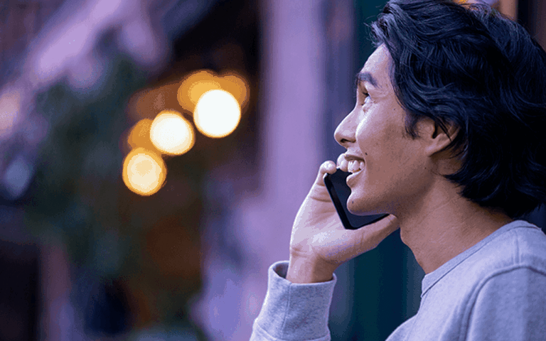 A man smiles while talking on the phone
