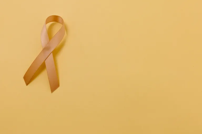 A yellow cancer ribbon on a yellow background