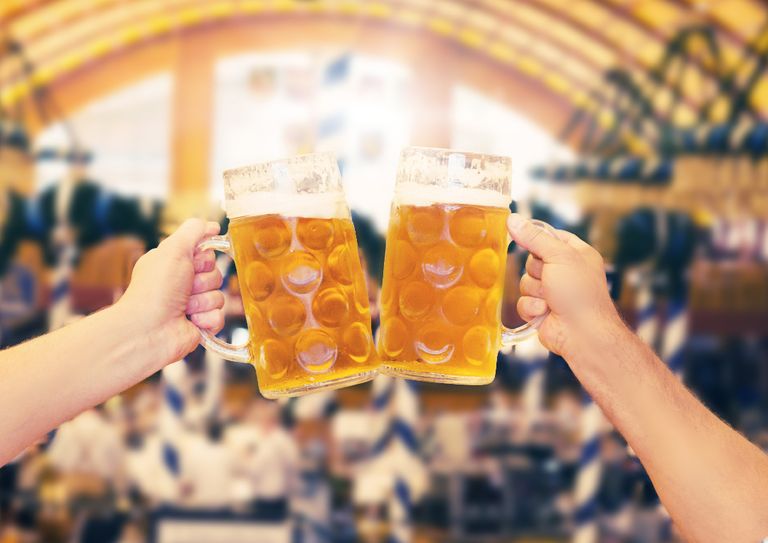 Two beer steins being held up in the air in a German beer hall.