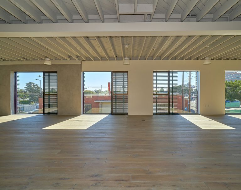 Interior view of a building. Four open spaces with sliding glass doors show the outside view. Fortina panels are running horizontally against the glass doors.