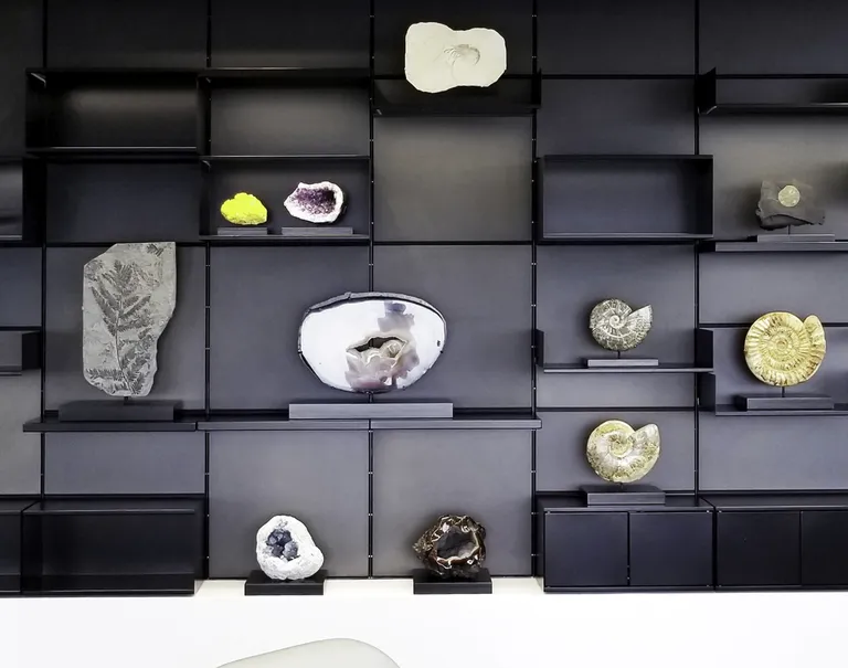 Miscellaneous small fossils and geodes are decorating black shelves held up against a black System 1224 wall.