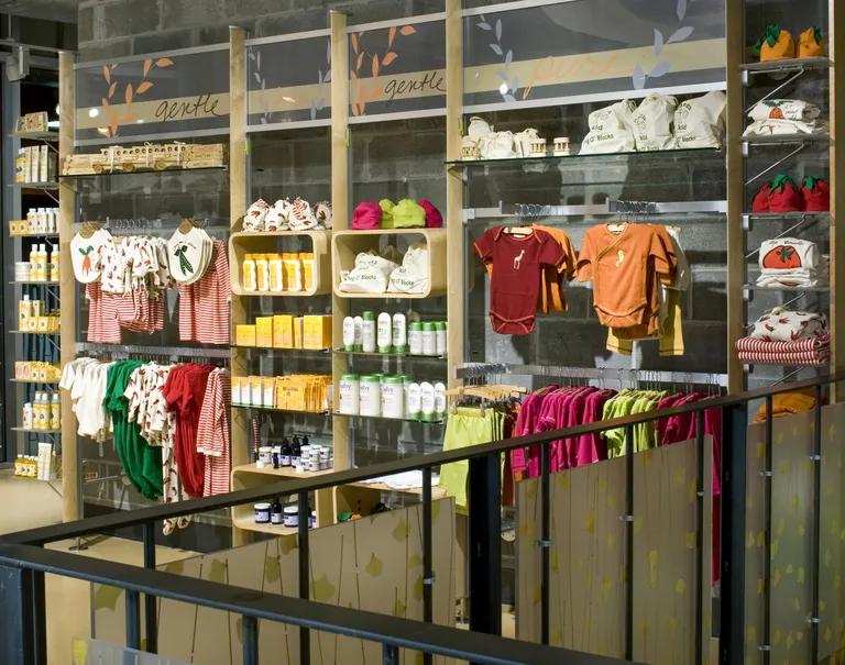 Various baby clothes and products are hung up on display on wooden shelves and metal racks.