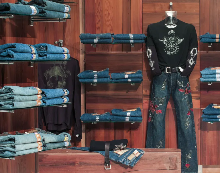 Jeans are placed on display on shelves held up by the Puck System on wooden walls.