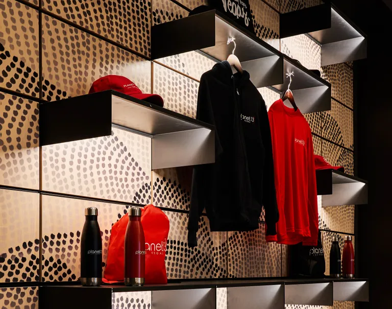 Close-up shot of dotted Infused Veneer panels working with black System 1224 shelves showcasing Planet 13 merchandise.