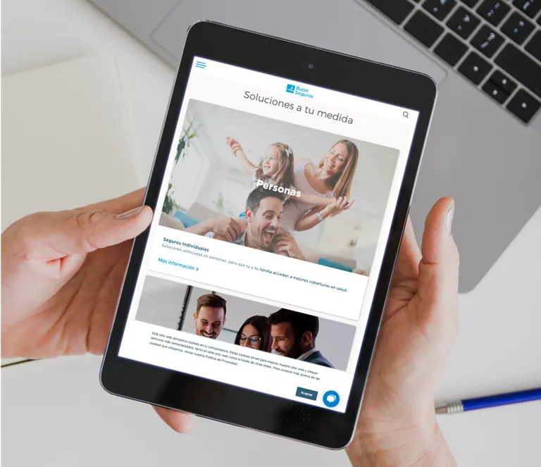 A hand holding a tablet displaying BUPA's website
